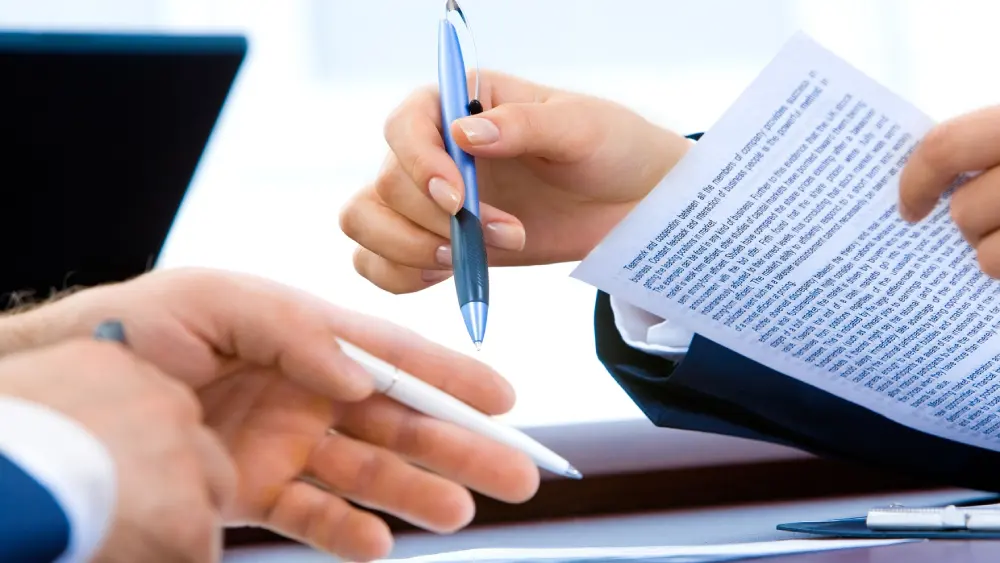 A person reviewing travel papers (passport, insurance policy) at an airport.