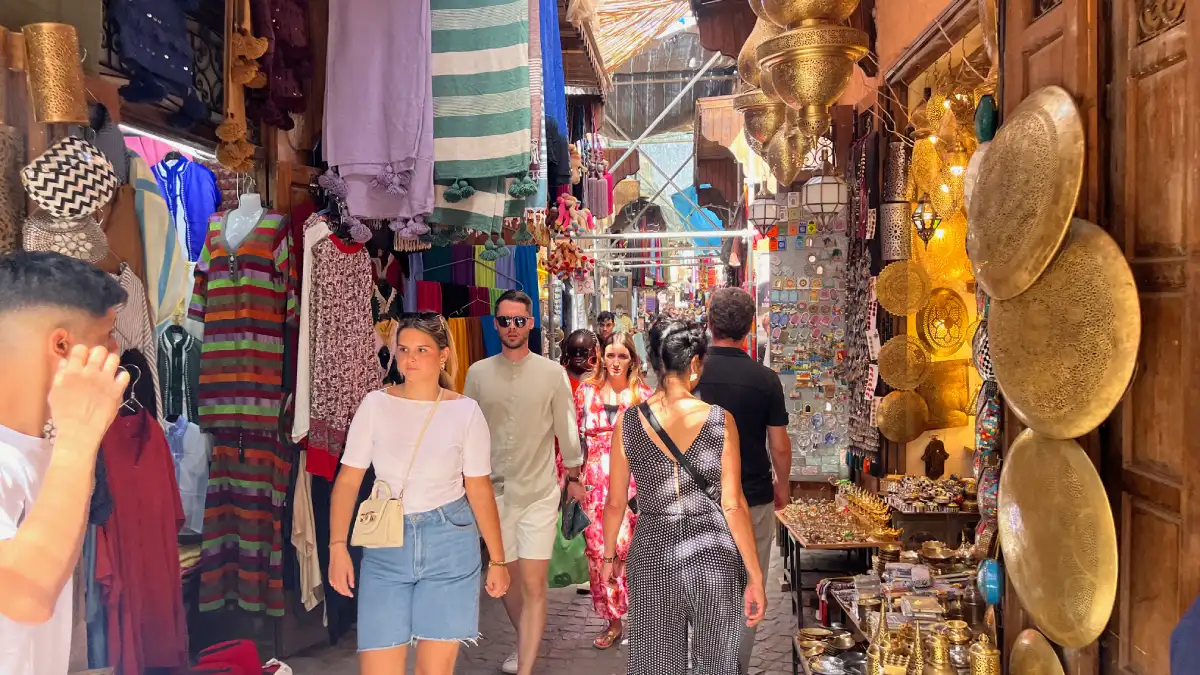 Visitors walking through a busy shopping lane in the Marrakech souks, one of the best things to do in Marrakech.