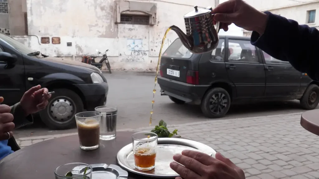 Moroccan tea ceremony etiquette: The traditional Moroccan high pour technique creating foam in a tea glass.
The traditional Moroccan high pour technique creating foam in a tea glass.