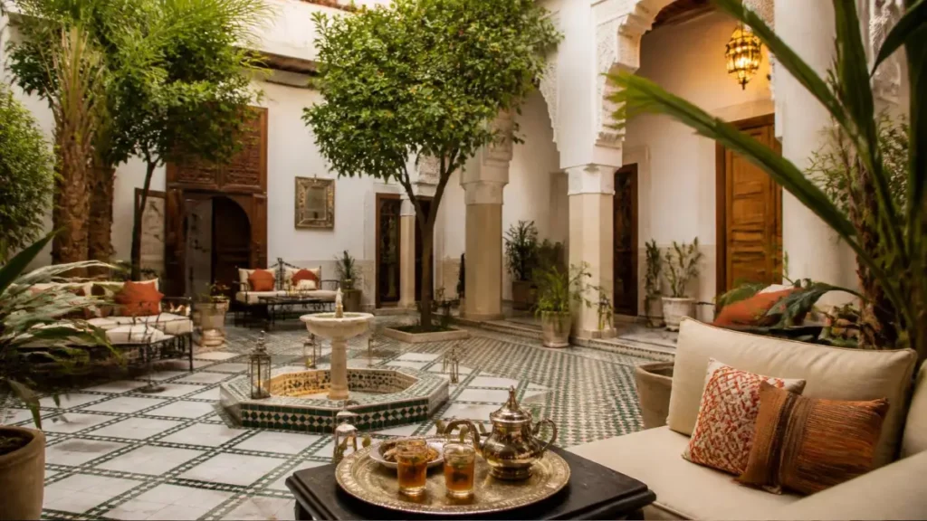Cozy Moroccan riad courtyard with fountain, plants, and cushioned seating showing authentic architecture and modern comfort.