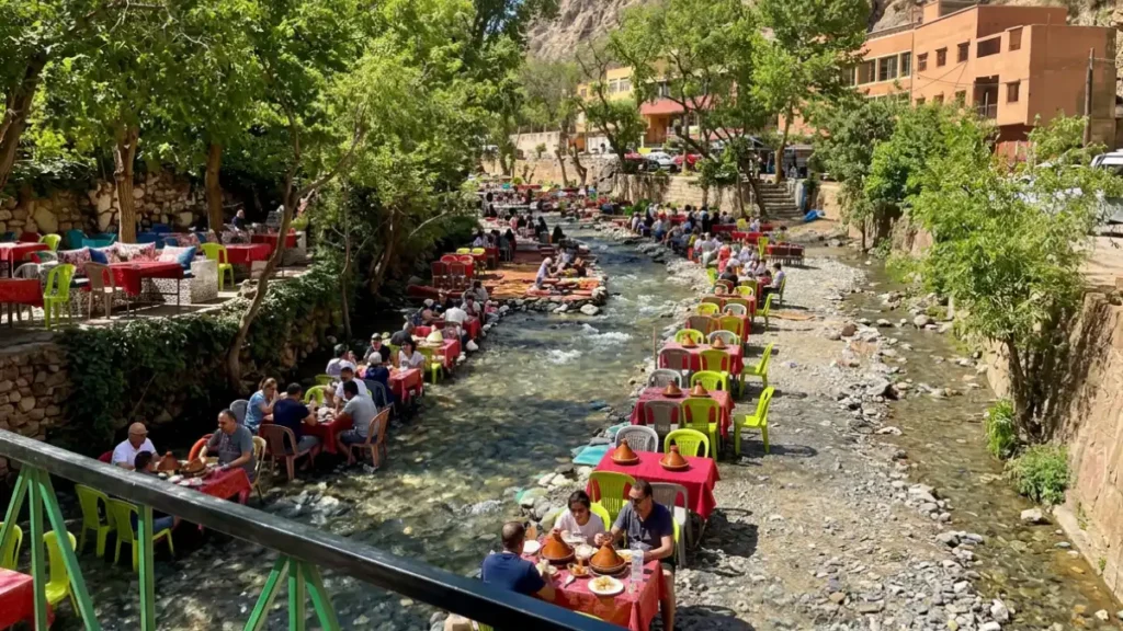 Colorful plastic tables and chairs set directly inside the shallow river of the Ourika Valley in Morocco.