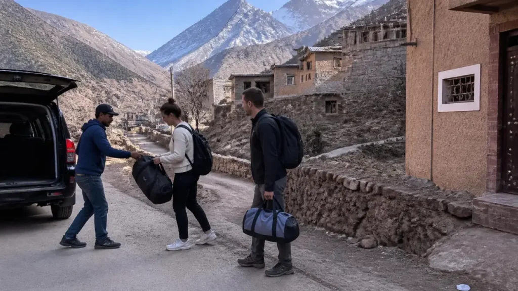 Travelers arriving in Imlil village with luggage assistance near stone houses in Morocco’s High Atlas Mountains