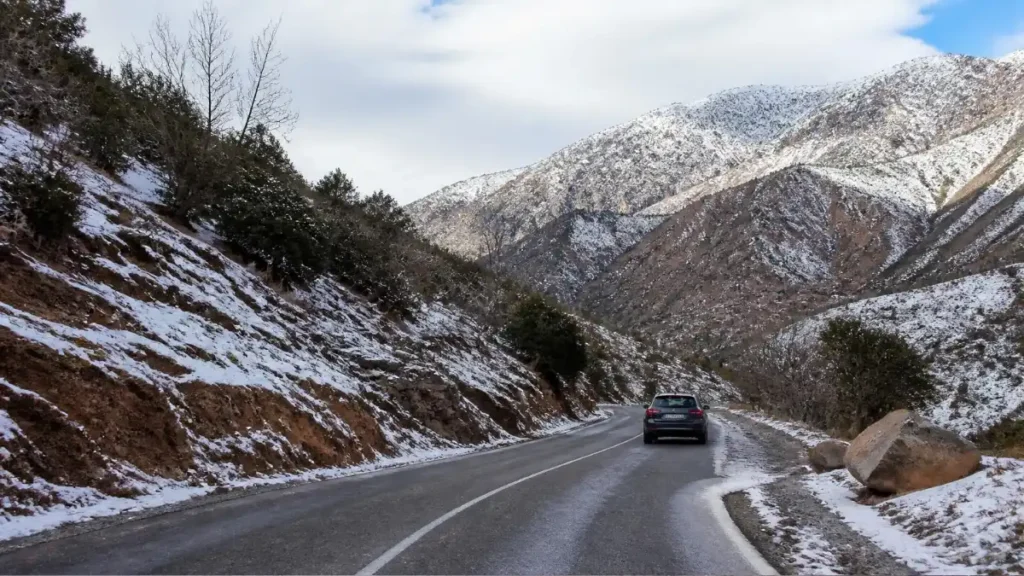 Paved road near Imlil with light winter snow beside the roadway
