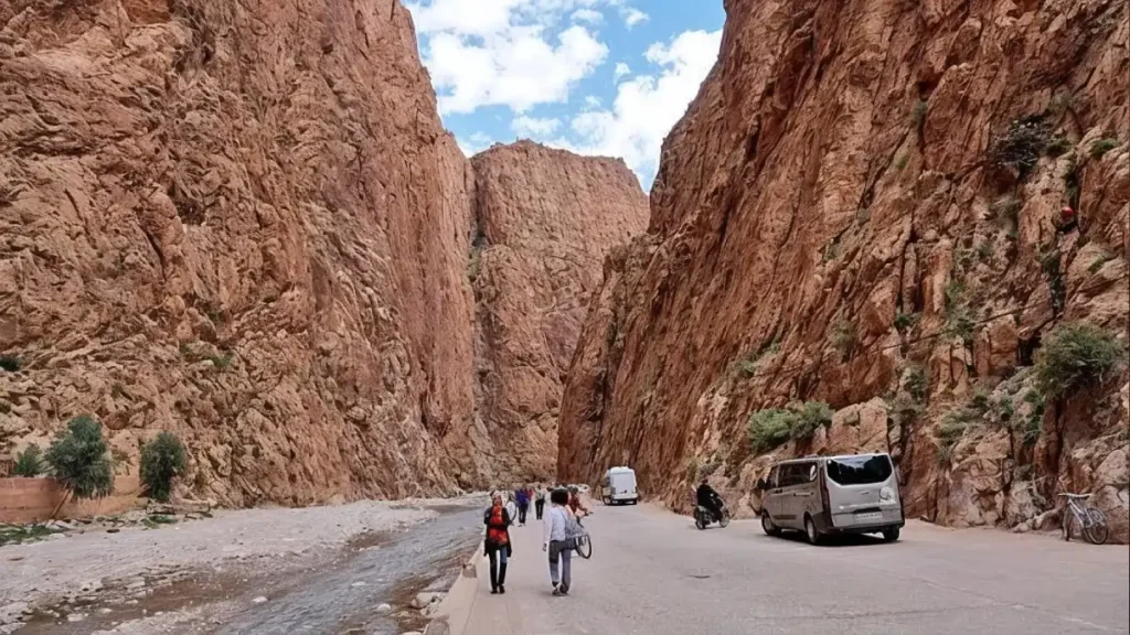 Travelers walking beneath the limestone cliffs of Todra Gorge on the way to Merzouga.