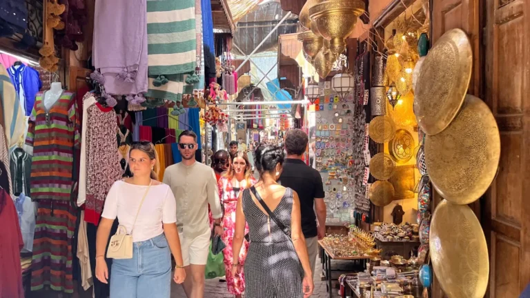 Shoppers walking through a colourful Marrakech market in the Medina