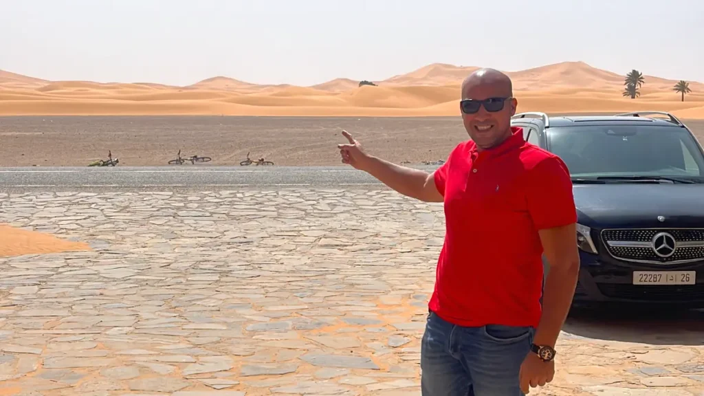 Local guide pointing toward the Erg Chebbi sand dunes near Merzouga