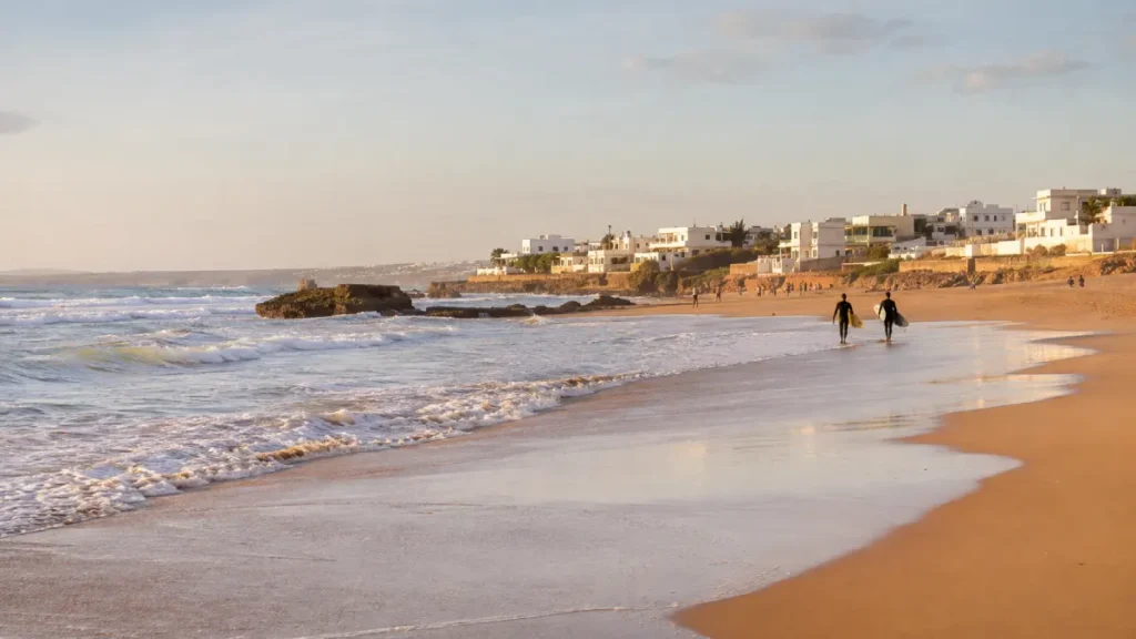 Surfers walking along Dar Bouazza beach near Casablanca