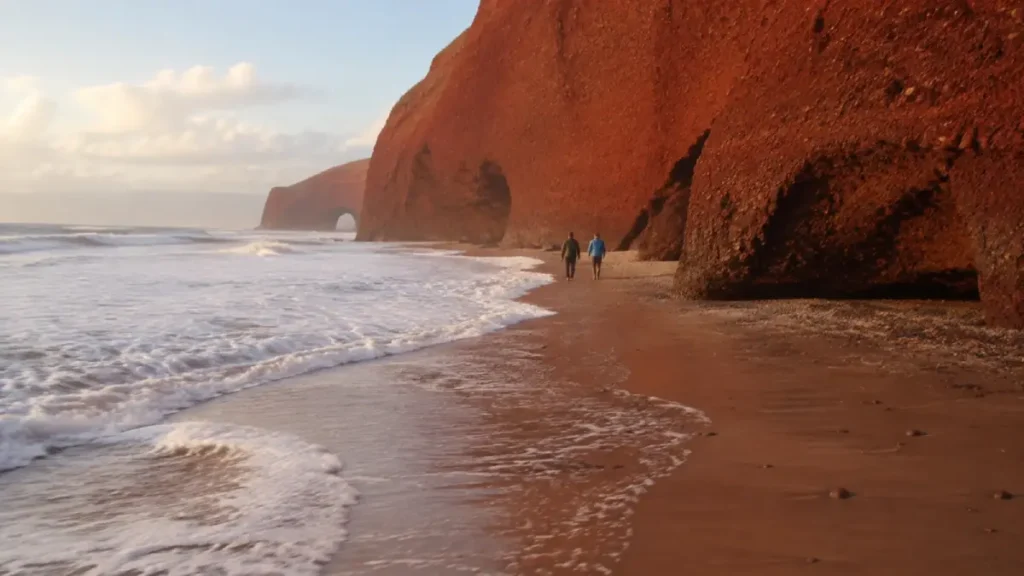 Incoming tide narrowing the walking route beneath Legzira’s cliffs