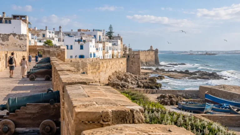 Travellers walking along Essaouira’s historic ramparts beside the Atlantic Ocean in June