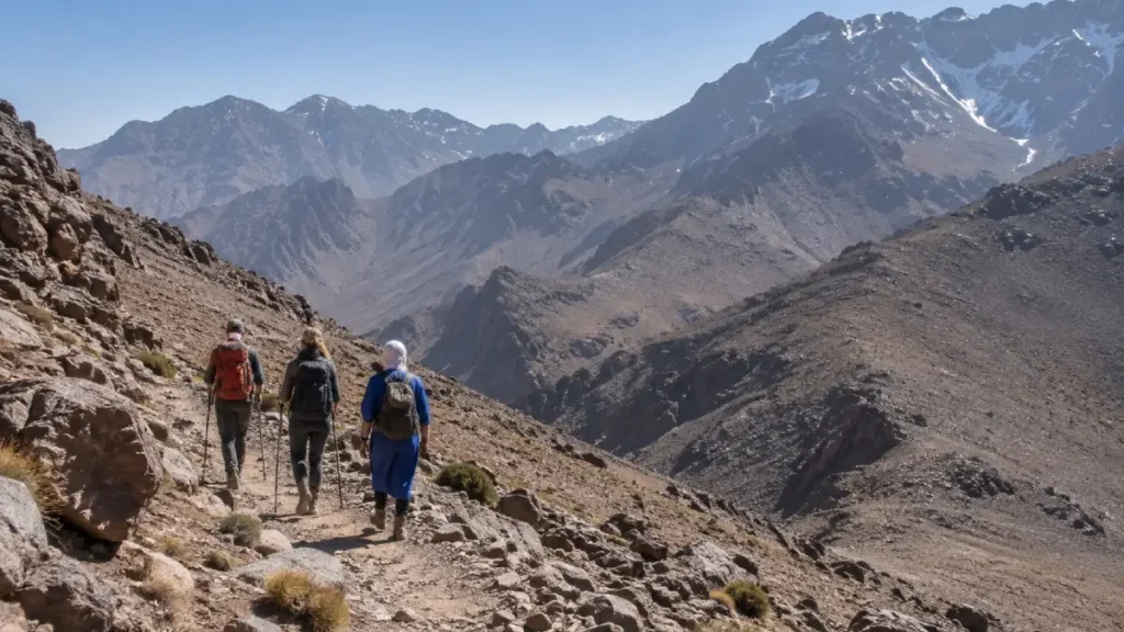 Mountain guide and hikers walking on the rocky Mount Toubkal route above Imlil