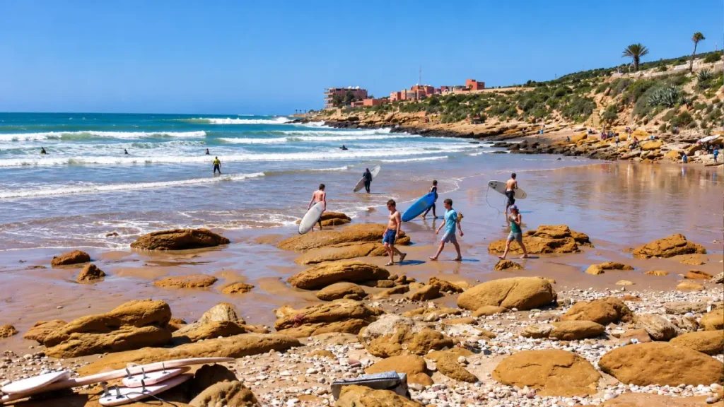 Surfers walking across the rocky shoreline at Panorama Beach in Taghazout Morocco
