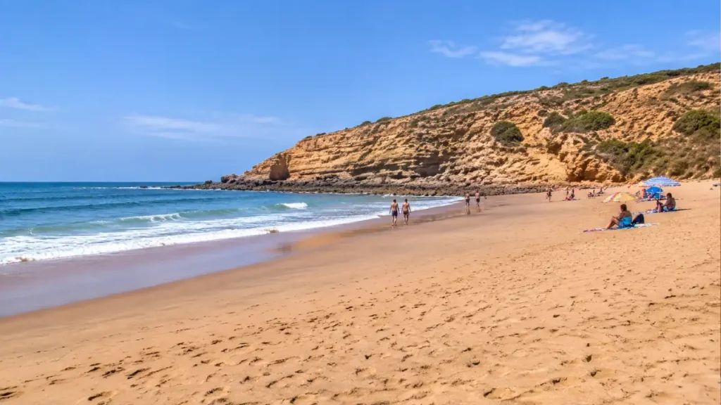 Paradise Beach near Asilah, Morocco, featuring golden sand, Atlantic waves, natural sandstone cliffs and visitors relaxing along the coastline.