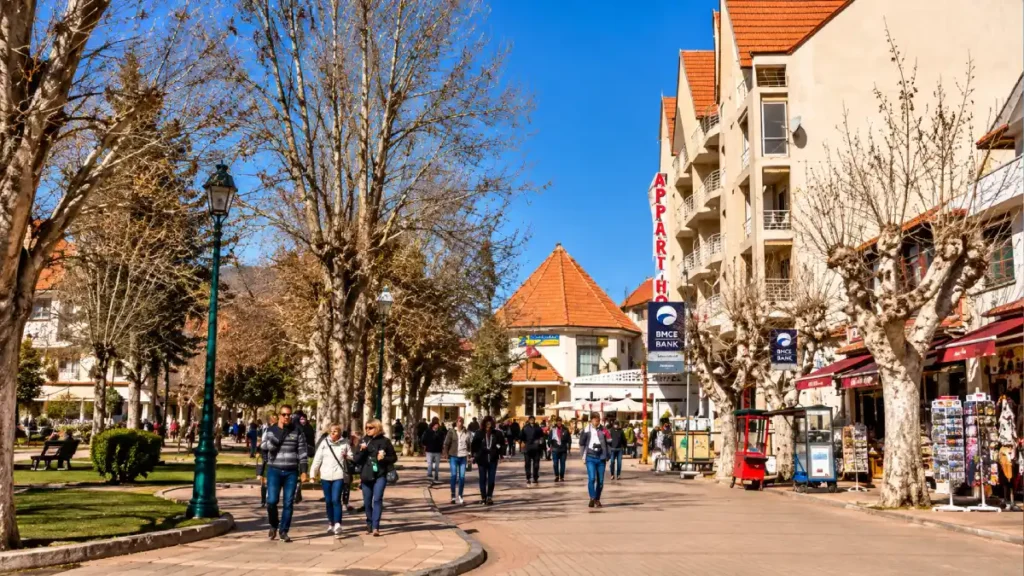 Ifrane city center in Morocco with red-roofed Alpine-style buildings, tree-lined pedestrian streets and visitors exploring the town