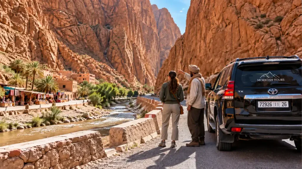 Traveler and Moroccan driver in changed outfits beside a black Toyota Prado TX at Todra Gorge